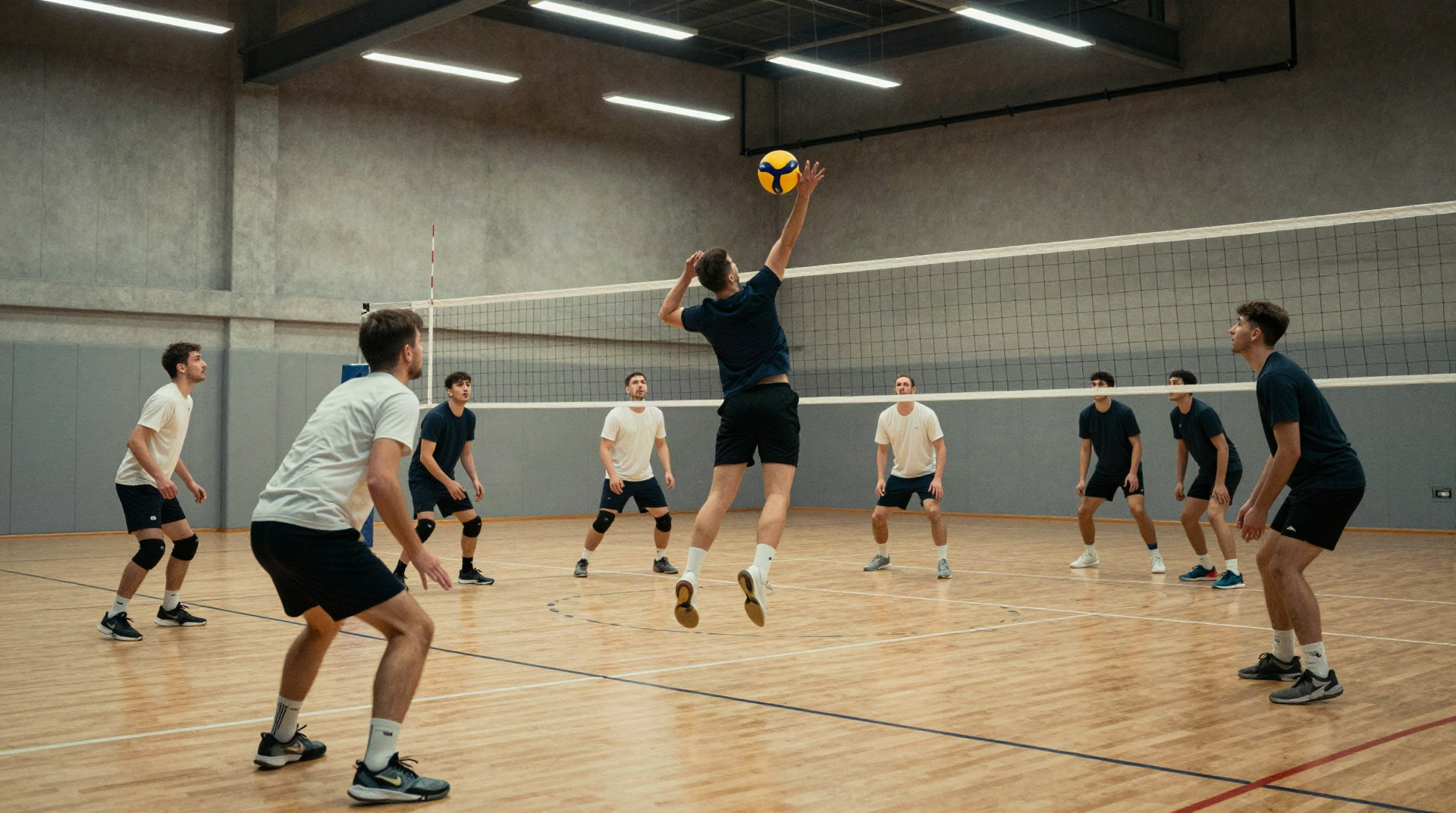 Сотрудники в спортивной форме играют в волейбол в большом спортзале.